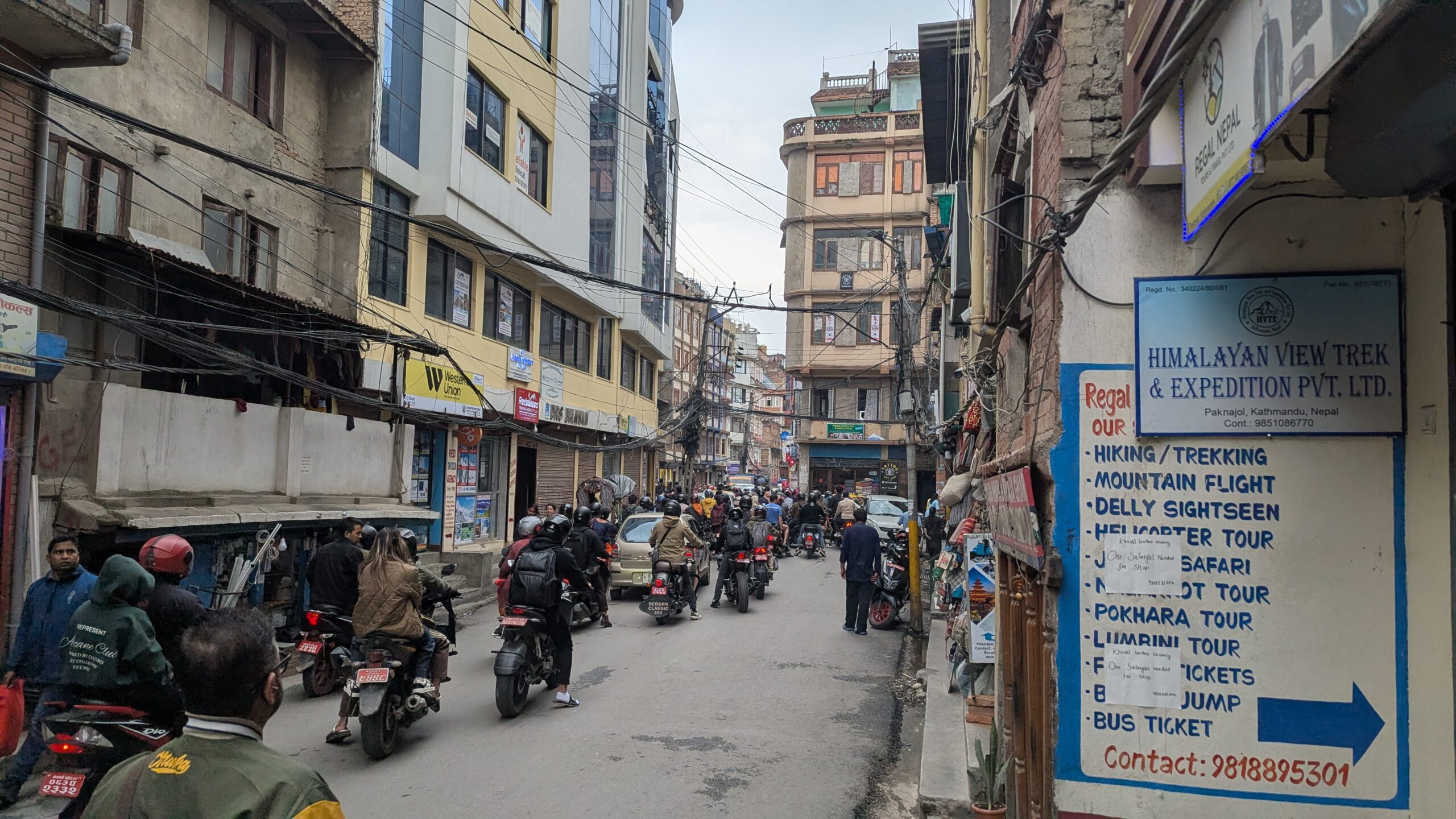 A narrow street filled with small motorcycles.